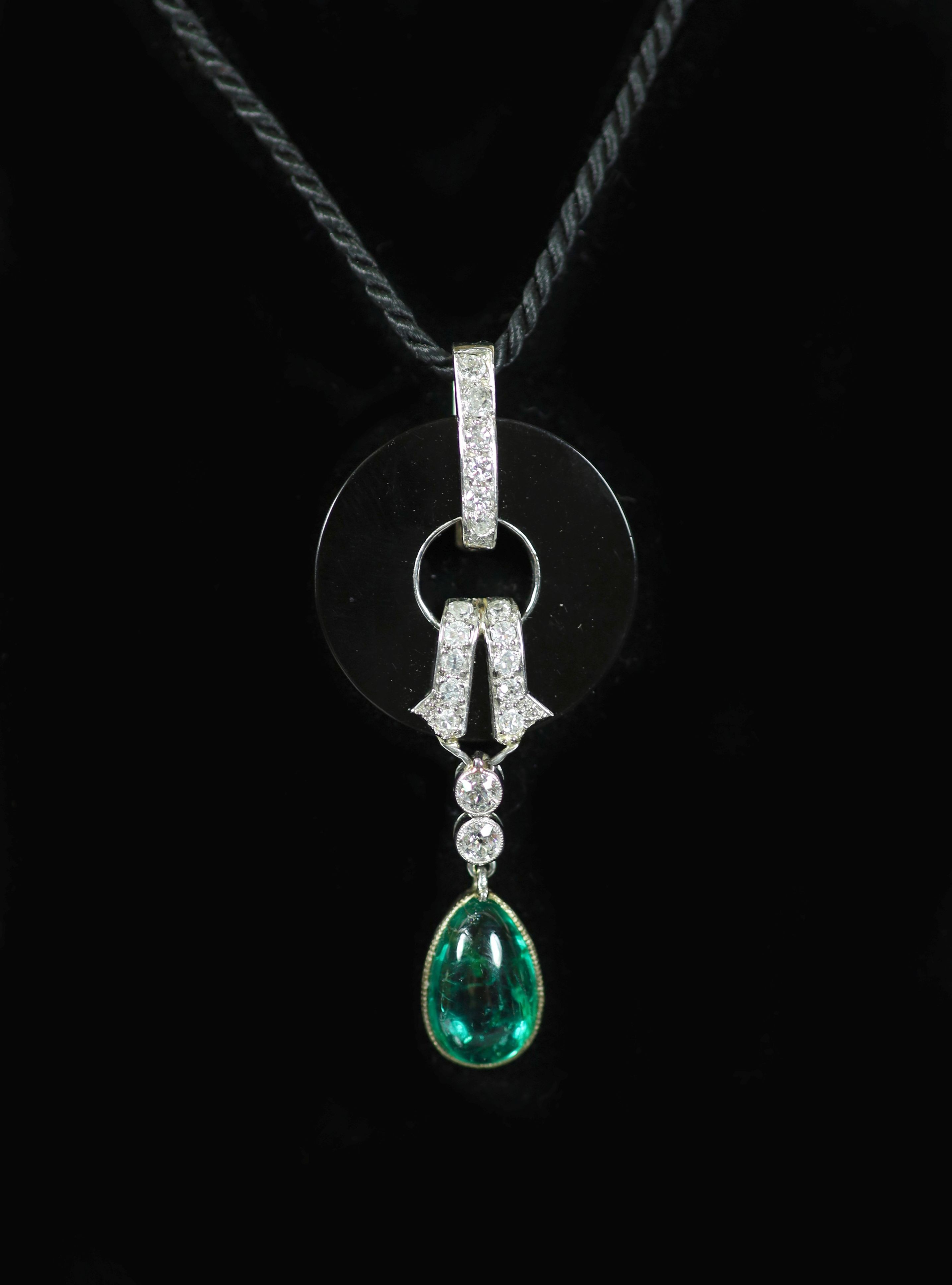 A French Art Deco style platinum, black onyx, diamond and pear cut cabochon emerald set drop pendant, on a black fabric cord